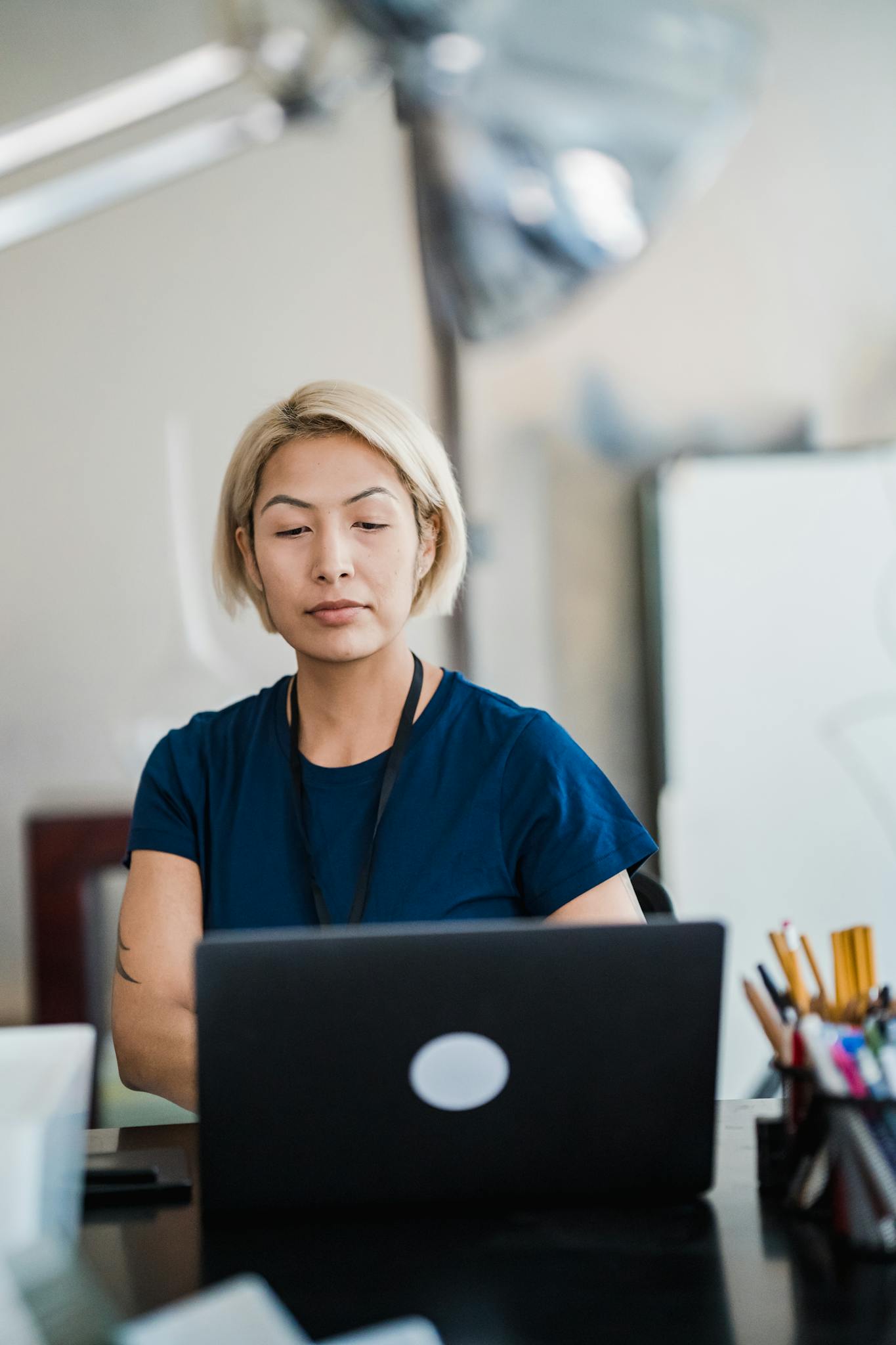 Professional woman working at a desk, focused on a laptop in an office setting.